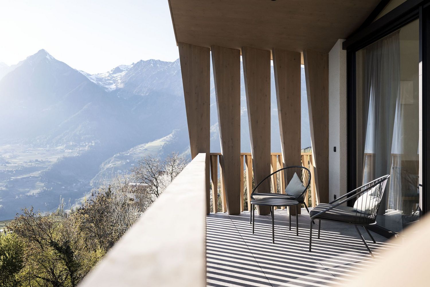 Balkon mit zwei Stühlen und Kissen, Holzelemente, Bergpanorama im Hintergrund