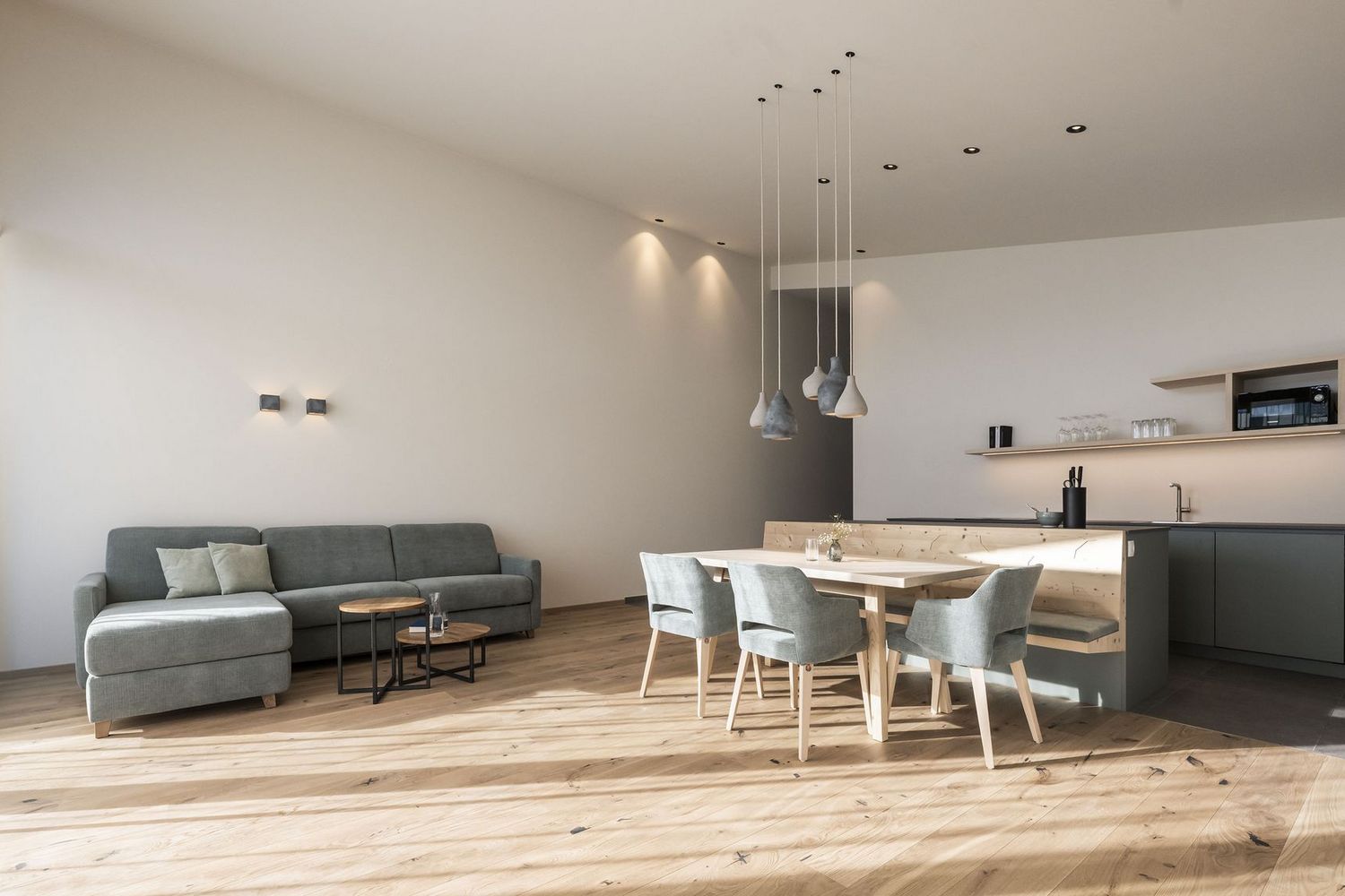Heller, moderner Wohn- und Essbereich mit grauem Sofa, Holztisch und Küchenzeile in neutralen Farben.